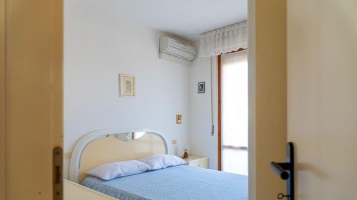 um quarto com uma cama com lençóis azuis e uma janela em Appartamento Il Marinaio em Porto Azzurro