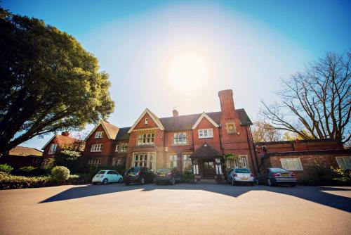 a large house with cars parked in front of it at Cantley House Hotel - Wokingham in Wokingham