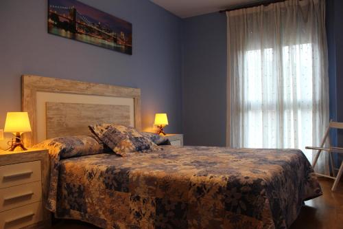 ein Schlafzimmer mit einem Bett, zwei Lampen und einem Fenster in der Unterkunft Adrimarcangas 2 in Cangas de Onís