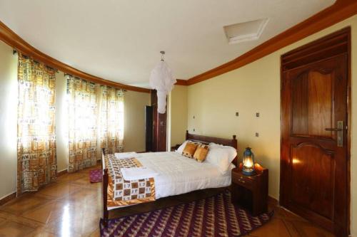 1 dormitorio con 1 cama y puerta de madera en Top of The World Lodge, en Kikangala