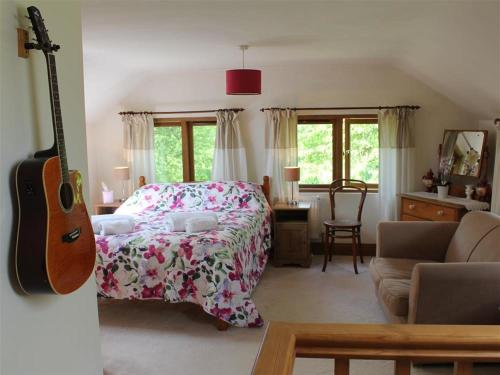 ein Schlafzimmer mit einem Bett und einer Gitarre in einem Zimmer in der Unterkunft The Cider Barn in Flaxley