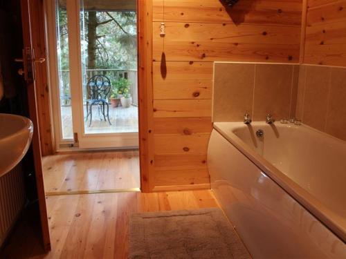 a bathroom with a tub and a wooden wall at Treetops in Parracombe