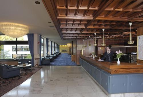 a lobby with a woman sitting at a bar at Maritim Hotel Bellevue Kiel in Kiel