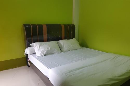 a green bedroom with a bed with white sheets and pillows at OYO 3487 Es Em Je Residence in Lubukpakam