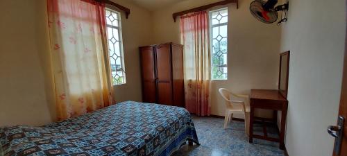 a bedroom with a bed and a desk and two windows at Allamanda Apartments - 100m Bain Boeuf Beach in Bain Boeuf