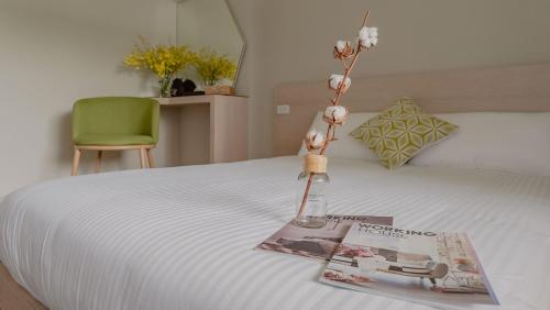a vase with flowers on a bed with a magazine at Night Home in Dongshan
