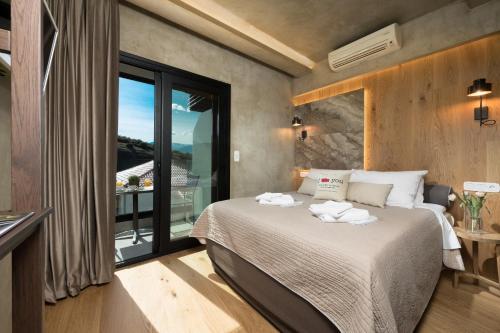 a bedroom with a bed and a large window at Tsikeli Boutique Hotel Meteora - Adults Friendly in Kalabaka