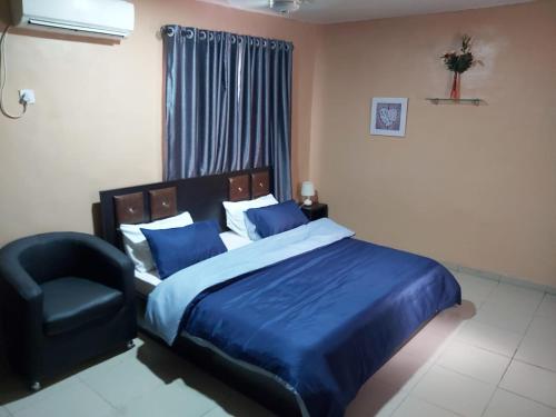 a bedroom with a blue bed and a chair at StayCation Suites And Apartment in Lagos