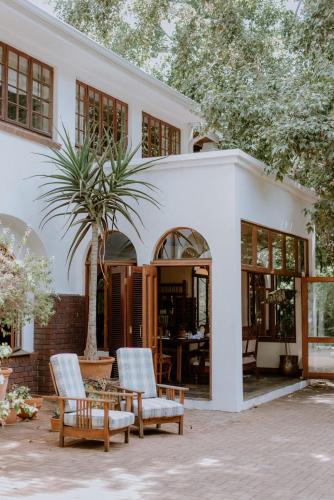 a white house with two chairs and a table at Kleinkaap Boutique Hotel in Centurion