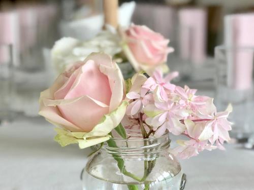 a glass vase filled with pink flowers on a table at Hotel Restaurant FIDI in Wolfsthal