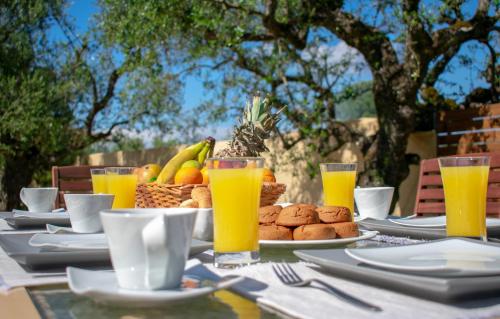 una mesa con platos de comida y vasos de jugo de naranja en Zante Lagos holiday homes Treehouse and Villa, en Vouyiáton