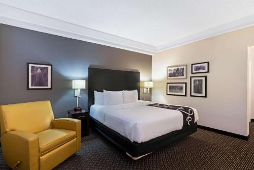 a hotel room with a bed and a chair at La Quinta by Wyndham Mesa Superstition Springs in Mesa