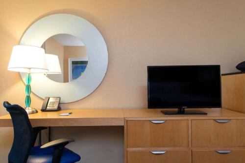 a room with a desk with a television and a mirror at La Quinta I-95 Deerfield Beach - Next to The Home Depot & Behind The Wawa in Deerfield Beach