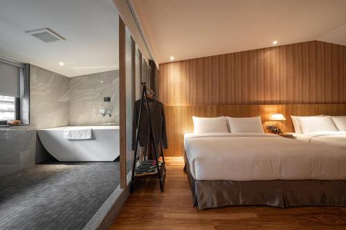 a hotel room with two beds and a bath tub at Yunoyado Onsen Hot Spring Hotel Deyang in Jiaoxi