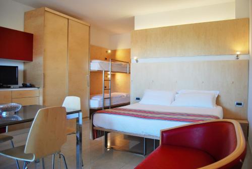 a bedroom with a bed and a chair and a kitchen at Aparthotel Albatros in Lignano Sabbiadoro
