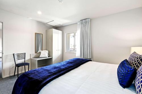 a bedroom with a large bed and a chair at The Suites Ashburton in Ashburton