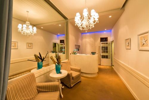 a living room with chairs and a table and chandeliers at Oasis Beach Hotel in Skala