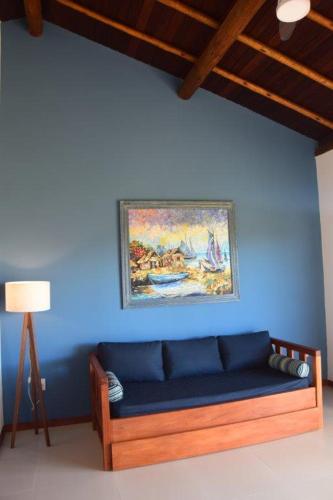 a blue couch against a blue wall with a painting at Carapitangui Pousada in Barra Grande