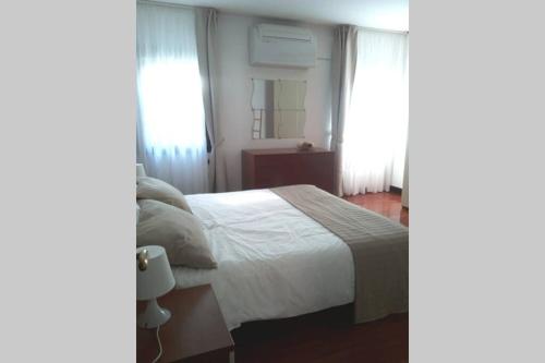 1 dormitorio con 1 cama blanca y 2 ventanas en Ai Cordami, en Venecia