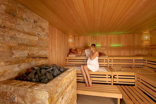 a woman and a man sitting in a sauna at SEETELHOTEL Nautic Usedom Hotel & Spa das Hotel für Wellness & Genuss auf Usedom in Ostseebad Koserow