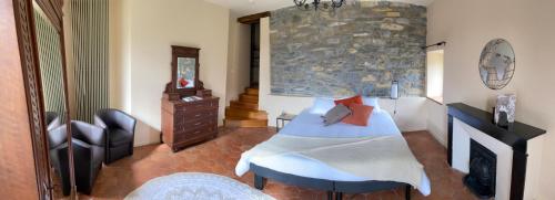 um quarto com uma cama e uma parede de pedra em Les Tilleuls em Saint-Georges-de-Luzençon