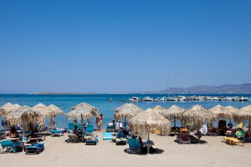 a beach with chairs and straw umbrellas and the water at Oasis Beach Hotel in Skala