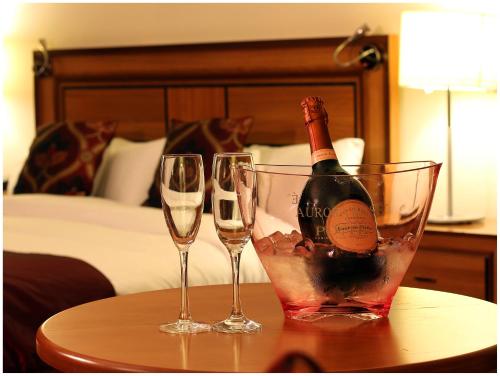 Dois copos de vinho e uma garrafa de vinho numa mesa em Blanco's Hotel em Port Talbot