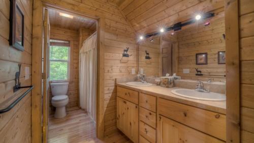 a log cabin bathroom with two sinks and a toilet at Cubs Cabin in Blue Ridge