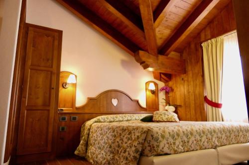 1 dormitorio con cama y techo de madera en Dream Hotel, en Macugnaga