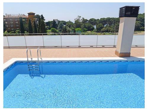 a blue swimming pool with a ladder in front of a building at SeaHomes Vacations, BEACH&POOL, in Fenals Beach in Lloret de Mar