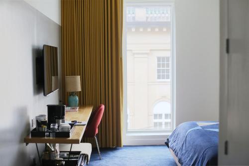 a bedroom with a desk and a bed and a window at The Durham Hotel in Durham