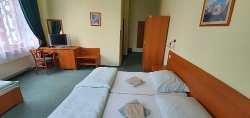 a hotel room with two beds and a desk at Penzión Rodina in Levoča