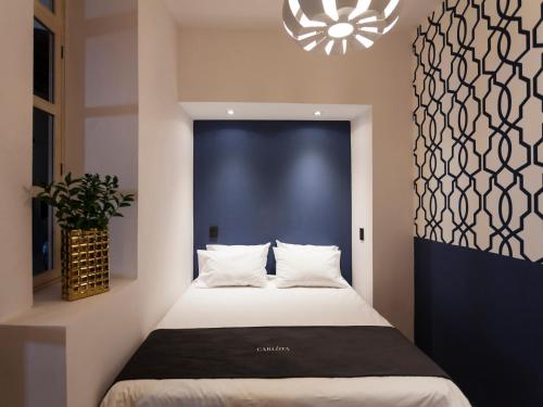 a bedroom with a bed with a blue wall and a chandelier at Carlota Sustainable Design Hotel in Quito