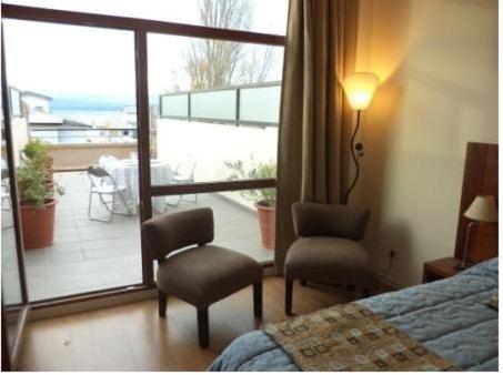 a bedroom with a bed and a chair and a balcony at Bariloche Downtown 2 in San Carlos de Bariloche