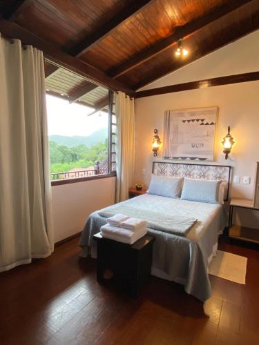a bedroom with a bed and a large window at Estalagem Alter Real in Pirenópolis
