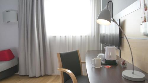 a desk with a lamp and a computer on it at Holiday Inn Express Molins de Rei, an IHG Hotel in Molins de Rei