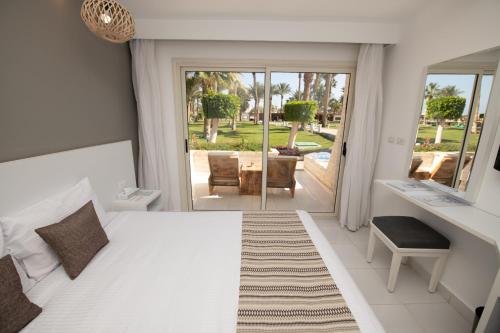 Meraki Resort - Adults Only في الغردقة: غرفة نوم بسرير وطاولة وكراسي