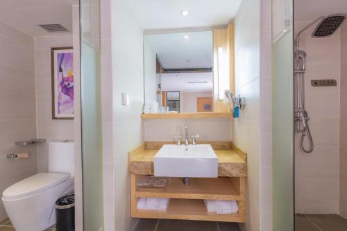 a bathroom with a sink and a toilet and a mirror at Lavande Hotel Zhuhai Gongbei Port Square in Zhuhai