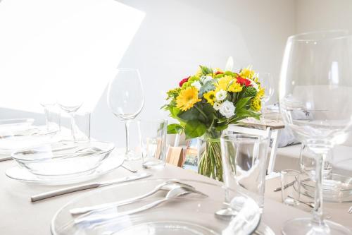 a white table with a vase of flowers on it at Chalet Hygge Saint Lary - gîtes de standing en coeur de village des Pyrénées in Saint-Lary-Soulan