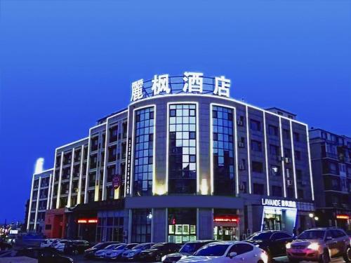 un gran edificio con coches estacionados en un estacionamiento en Lavande Hotels·Dalian Xinghai Park en Dalian