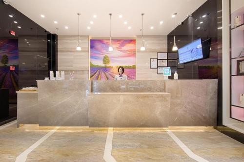 a lobby with a counter with a woman on the wall at Lavande Hotels·Kunshan Renmin Road in Suzhou