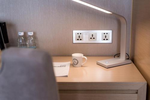 a desk with a coffee cup and a lamp on it at Lavande Hotels·Guangzhou Dongpu Bus Terminal in Guangzhou