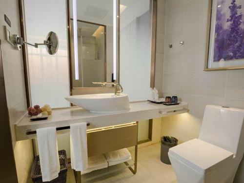 a bathroom with a sink and a toilet and a mirror at Lavande Hotels·Foshan Bijiang Light Rail Country Garden Headquarters in Guangzhou
