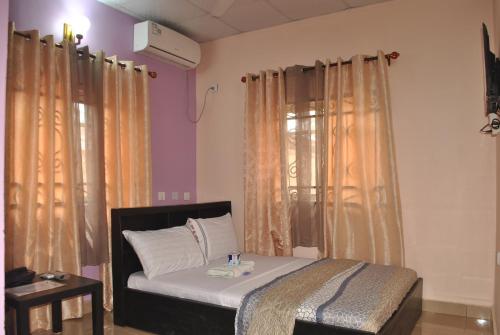 Sino Guesthouse في Nkpor: سرير في غرفة مع الستائر وسيدكس sidx sidx