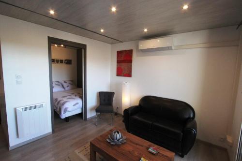 - un salon avec un fauteuil en cuir noir et un lit dans l'établissement Le Balcon sur la Cité, à Carcassonne