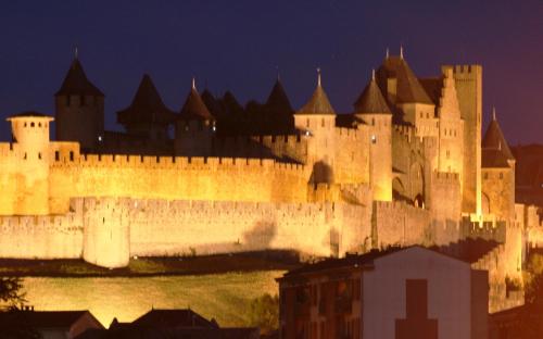 un grand château éclairé la nuit dans l'établissement Le Balcon sur la Cité, à Carcassonne