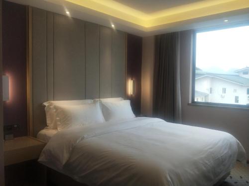 a bedroom with a large white bed with a window at Lavande Hotels·Guilin Central Square Elephant Trunk Hill Scenic Area in Guilin