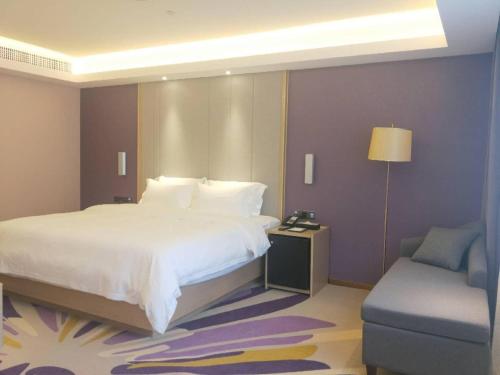 a bedroom with a large white bed and a chair at Lavande Hotels·Guilin Central Square Elephant Trunk Hill Scenic Area in Guilin