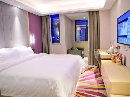 um quarto de hotel com uma cama branca e uma televisão em Lavande Hotels·Shenzhen North Railway Station Longhua Bus Terminal em Shenzhen