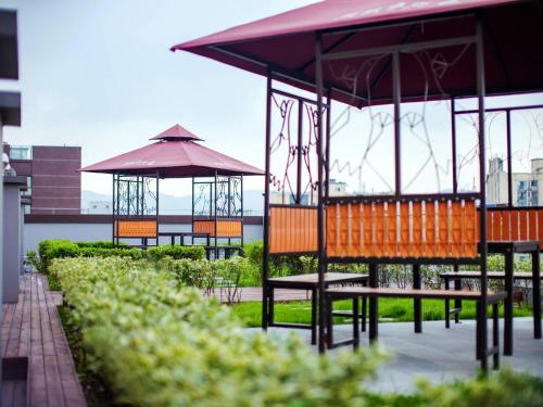 a group of benches and umbrellas in a park at Lavande Hotel Chongqing West Station Baguo Cheng in Chongqing